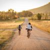 Dos niños en bicicleta por un camino de pueblo rural en el atardecer de verano